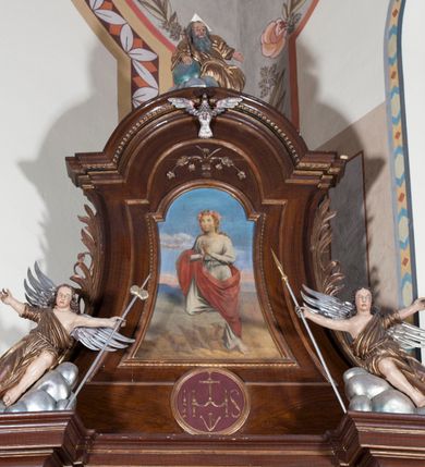 Zdjęcie nr 3: Dwie pełnoplastyczne przyścienne rzeźby, przedstawiające w całej postaci dwa siedzące w antytetycznych pozach uskrzydlone anioły. W rozłożonych na boki rękach trzymają: trzcinę z gąbką (anioł po lewej) i dzidę (anioł po prawej). Anioły, okryte złotą draperią, siedzą ukośnie na srebrzystych obłokach.  