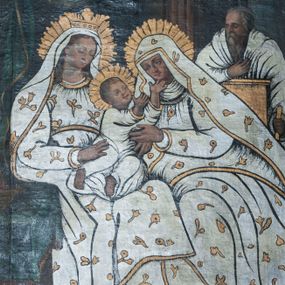 Zdjęcie nr 1: Obraz w kształcie stojącego prostokąta zamkniętego łukiem półpełnym nadwieszonym, o kompozycji dwustrefowej. W strefie dolnej przedstawienie świętej Anny Samotrzeć. Pośrodku siedzą na ławie Maria (po lewej i św. Anna po prawej, ukazane w całych postaciach, w trzech czwartych zwrócone ku sobie. Maria, z głową przechyloną na lewą stronę, prawą ręką podtrzymuje małego Jezusa siedzącego na jej kolanach. Św. Anna mocno przechylona w stronę Marii lewą dłonią dotyka Jezusa, który siedząc na kolanach Matki wyciąga ręce ku Babce ręce. Maria i św. Anna okryte jednakowymi drewnianymi sukienkami i maforionami zdobionymi motywami gałązek kwiatowych. Jezus w długiej białej sukience z długimi rękawami. Z tyłu po prawej stronie obrazu święty Józef widoczny w półpostaci. W tle kotara i fragmenty monumentalnej architektury. W strefie górnej na osi Gołębica Ducha Świętego na tle spływającej z góry smugi światła, po bokach aniołowie.