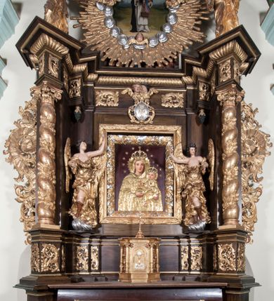 Zdjęcie nr 3: Obraz w kształcie koła (tondo). Św. Jacek przedstawiony w całej postaci, w ujęciu w trzech czwartych, zwrócony lekko w lewo, w habicie dominikańskim. Głowa z wygoloną tonsurą otoczona nimbem. W prawej ręce trzyma przed sobą kustodię z hostią, lewą ręką przyciska do ciała okazałą, polichromowaną rzeźbę z przedstawieniem Matki Boskiej z Dzieciątkiem i Chrystusem Ukrzyżowanym na Drzewie Życia (Matka Boska Jackowa). Święty stoi na rozległej murawie, w tle daleki pejzaż miasta i skłębione ciemne chmury.