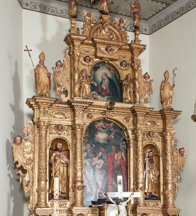 Zdjęcie nr 2: Ołtarz architektoniczny, z wydzieloną predellą, trójosiowy, dwukondygnacyjny ze zwieńczeniem. Predella węższa od nastawy, rozszerzająca się ku górze. Dolna kondygnacja artykułowana kolumnami o trzonach przedzielonych opaską w jednej trzeciej wysokości, zdobionych główkami aniołków, girlandami i dekoracją kandelabrową; kapitele kompozytowe; w osiach zewnętrznych kolumny nadwieszone na konsolach, w osiach wewnętrznych ustawione na postumentach. Kolumny wspierają belkowanie i gzyms występujące nad nimi. W polu środkowym prostokątna nisza zamknięta półkoliście, w niej obraz: Chrzest Chrystusa; w polach bocznych mniejsze nisze prostokątne zamknięte półkoliście, muszlowe, w nich rzeźby: Św. Piotr i Św. Paweł. Górna kondygnacja ujęta kolumnami o kręconych trzonach z dekoracją roślinną i kompozytowych kapitelach, wspierającymi belkowanie i profilowany gzyms. W polu środkowym nisza zamknięta półkoliście w niej obraz: Matka Boska z Dzieciątkiem. Po bokach obrazu rzeźby: Św. Anna (?) i Św. Marcin (?). Dolna i górna kondygnacje flankowane rzeźbionymi, ażurowymi uszakami z motywem herm aniołów. W osiach kolumn dolnej kondygnacji rzeźby: Św. Wojciech i Św. Stanisław. Zwieńczenie w kształcie półkolistego przyczółka wspartego na konsoli wchodzącej w pole górnej kondygnacji. W polu zwieńczenia płaskorzeźbione, półplastyczne przedstawienie Boga Ojca w popiersiu, flankowane wolutami z półpostaciami dwóch uskrzydlonych aniołów. Po bokach w zwieńczeniu, w osiach kolumn górnej kondygnacji, rzeźby uskrzydlonych aniołów.   W szczycie ołtarza na konsoli rzeźba: Św. Michał Archanioł. W przyłuczach nisz na obrazy, ponad niszami na rzeźby, w predelli, na konsolach i postumentach kolumn dolnej kondygnacji oraz na konsoli poniżej zwieńczenia uskrzydlone główki aniołków. Ponadto poniżej nisz, w tle kolumn oraz na belkowaniu płyciny ornamentalne z motywów roślinnych i motywy rautów. Struktura ołtarza, rzeźby i ornamenty złocone, karnacje i włosy polichromowane.  
