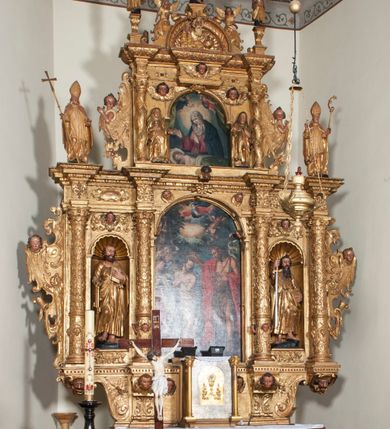 Zdjęcie nr 1: Ołtarz architektoniczny, z wydzieloną predellą, trójosiowy, dwukondygnacyjny ze zwieńczeniem. Predella węższa od nastawy, rozszerzająca się ku górze. Dolna kondygnacja artykułowana kolumnami o trzonach przedzielonych opaską w jednej trzeciej wysokości, zdobionych główkami aniołków, girlandami i dekoracją kandelabrową; kapitele kompozytowe; w osiach zewnętrznych kolumny nadwieszone na konsolach, w osiach wewnętrznych ustawione na postumentach. Kolumny wspierają belkowanie i gzyms występujące nad nimi. W polu środkowym prostokątna nisza zamknięta półkoliście, w niej obraz: Chrzest Chrystusa; w polach bocznych mniejsze nisze prostokątne zamknięte półkoliście, muszlowe, w nich rzeźby: Św. Piotr i Św. Paweł. Górna kondygnacja ujęta kolumnami o kręconych trzonach z dekoracją roślinną i kompozytowych kapitelach, wspierającymi belkowanie i profilowany gzyms. W polu środkowym nisza zamknięta półkoliście w niej obraz: Matka Boska z Dzieciątkiem. Po bokach obrazu rzeźby: Św. Anna (?) i Św. Marcin (?). Dolna i górna kondygnacje flankowane rzeźbionymi, ażurowymi uszakami z motywem herm aniołów. W osiach kolumn dolnej kondygnacji rzeźby: Św. Wojciech i Św. Stanisław. Zwieńczenie w kształcie półkolistego przyczółka wspartego na konsoli wchodzącej w pole górnej kondygnacji. W polu zwieńczenia płaskorzeźbione, półplastyczne przedstawienie Boga Ojca w popiersiu, flankowane wolutami z półpostaciami dwóch uskrzydlonych aniołów. Po bokach w zwieńczeniu, w osiach kolumn górnej kondygnacji, rzeźby uskrzydlonych aniołów.   W szczycie ołtarza na konsoli rzeźba: Św. Michał Archanioł. W przyłuczach nisz na obrazy, ponad niszami na rzeźby, w predelli, na konsolach i postumentach kolumn dolnej kondygnacji oraz na konsoli poniżej zwieńczenia uskrzydlone główki aniołków. Ponadto poniżej nisz, w tle kolumn oraz na belkowaniu płyciny ornamentalne z motywów roślinnych i motywy rautów. Struktura ołtarza, rzeźby i ornamenty złocone, karnacje i włosy polichromowane.  
