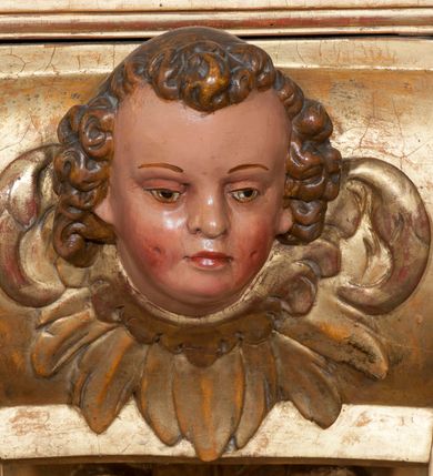 Zdjęcie nr 44: Ołtarz architektoniczny, z wydzieloną predellą, trójosiowy, dwukondygnacyjny ze zwieńczeniem. Predella węższa od nastawy, rozszerzająca się ku górze. Dolna kondygnacja artykułowana kolumnami o trzonach przedzielonych opaską w jednej trzeciej wysokości, zdobionych główkami aniołków, girlandami i dekoracją kandelabrową; kapitele kompozytowe; w osiach zewnętrznych kolumny nadwieszone na konsolach, w osiach wewnętrznych ustawione na postumentach. Kolumny wspierają belkowanie i gzyms występujące nad nimi. W polu środkowym prostokątna nisza zamknięta półkoliście, w niej obraz: Chrzest Chrystusa; w polach bocznych mniejsze nisze prostokątne zamknięte półkoliście, muszlowe, w nich rzeźby: Św. Piotr i Św. Paweł. Górna kondygnacja ujęta kolumnami o kręconych trzonach z dekoracją roślinną i kompozytowych kapitelach, wspierającymi belkowanie i profilowany gzyms. W polu środkowym nisza zamknięta półkoliście w niej obraz: Matka Boska z Dzieciątkiem. Po bokach obrazu rzeźby: Św. Anna (?) i Św. Marcin (?). Dolna i górna kondygnacje flankowane rzeźbionymi, ażurowymi uszakami z motywem herm aniołów. W osiach kolumn dolnej kondygnacji rzeźby: Św. Wojciech i Św. Stanisław. Zwieńczenie w kształcie półkolistego przyczółka wspartego na konsoli wchodzącej w pole górnej kondygnacji. W polu zwieńczenia płaskorzeźbione, półplastyczne przedstawienie Boga Ojca w popiersiu, flankowane wolutami z półpostaciami dwóch uskrzydlonych aniołów. Po bokach w zwieńczeniu, w osiach kolumn górnej kondygnacji, rzeźby uskrzydlonych aniołów.   W szczycie ołtarza na konsoli rzeźba: Św. Michał Archanioł. W przyłuczach nisz na obrazy, ponad niszami na rzeźby, w predelli, na konsolach i postumentach kolumn dolnej kondygnacji oraz na konsoli poniżej zwieńczenia uskrzydlone główki aniołków. Ponadto poniżej nisz, w tle kolumn oraz na belkowaniu płyciny ornamentalne z motywów roślinnych i motywy rautów. Struktura ołtarza, rzeźby i ornamenty złocone, karnacje i włosy polichromowane.  
