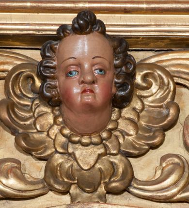 Zdjęcie nr 49: Ołtarz architektoniczny, z wydzieloną predellą, trójosiowy, dwukondygnacyjny ze zwieńczeniem. Predella węższa od nastawy, rozszerzająca się ku górze. Dolna kondygnacja artykułowana kolumnami o trzonach przedzielonych opaską w jednej trzeciej wysokości, zdobionych główkami aniołków, girlandami i dekoracją kandelabrową; kapitele kompozytowe; w osiach zewnętrznych kolumny nadwieszone na konsolach, w osiach wewnętrznych ustawione na postumentach. Kolumny wspierają belkowanie i gzyms występujące nad nimi. W polu środkowym prostokątna nisza zamknięta półkoliście, w niej obraz: Chrzest Chrystusa; w polach bocznych mniejsze nisze prostokątne zamknięte półkoliście, muszlowe, w nich rzeźby: Św. Piotr i Św. Paweł. Górna kondygnacja ujęta kolumnami o kręconych trzonach z dekoracją roślinną i kompozytowych kapitelach, wspierającymi belkowanie i profilowany gzyms. W polu środkowym nisza zamknięta półkoliście w niej obraz: Matka Boska z Dzieciątkiem. Po bokach obrazu rzeźby: Św. Anna (?) i Św. Marcin (?). Dolna i górna kondygnacje flankowane rzeźbionymi, ażurowymi uszakami z motywem herm aniołów. W osiach kolumn dolnej kondygnacji rzeźby: Św. Wojciech i Św. Stanisław. Zwieńczenie w kształcie półkolistego przyczółka wspartego na konsoli wchodzącej w pole górnej kondygnacji. W polu zwieńczenia płaskorzeźbione, półplastyczne przedstawienie Boga Ojca w popiersiu, flankowane wolutami z półpostaciami dwóch uskrzydlonych aniołów. Po bokach w zwieńczeniu, w osiach kolumn górnej kondygnacji, rzeźby uskrzydlonych aniołów.   W szczycie ołtarza na konsoli rzeźba: Św. Michał Archanioł. W przyłuczach nisz na obrazy, ponad niszami na rzeźby, w predelli, na konsolach i postumentach kolumn dolnej kondygnacji oraz na konsoli poniżej zwieńczenia uskrzydlone główki aniołków. Ponadto poniżej nisz, w tle kolumn oraz na belkowaniu płyciny ornamentalne z motywów roślinnych i motywy rautów. Struktura ołtarza, rzeźby i ornamenty złocone, karnacje i włosy polichromowane.  
