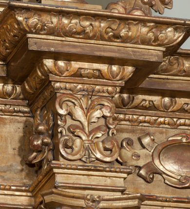 Zdjęcie nr 55: Ołtarz architektoniczny, z wydzieloną predellą, trójosiowy, dwukondygnacyjny ze zwieńczeniem. Predella węższa od nastawy, rozszerzająca się ku górze. Dolna kondygnacja artykułowana kolumnami o trzonach przedzielonych opaską w jednej trzeciej wysokości, zdobionych główkami aniołków, girlandami i dekoracją kandelabrową; kapitele kompozytowe; w osiach zewnętrznych kolumny nadwieszone na konsolach, w osiach wewnętrznych ustawione na postumentach. Kolumny wspierają belkowanie i gzyms występujące nad nimi. W polu środkowym prostokątna nisza zamknięta półkoliście, w niej obraz: Chrzest Chrystusa; w polach bocznych mniejsze nisze prostokątne zamknięte półkoliście, muszlowe, w nich rzeźby: Św. Piotr i Św. Paweł. Górna kondygnacja ujęta kolumnami o kręconych trzonach z dekoracją roślinną i kompozytowych kapitelach, wspierającymi belkowanie i profilowany gzyms. W polu środkowym nisza zamknięta półkoliście w niej obraz: Matka Boska z Dzieciątkiem. Po bokach obrazu rzeźby: Św. Anna (?) i Św. Marcin (?). Dolna i górna kondygnacje flankowane rzeźbionymi, ażurowymi uszakami z motywem herm aniołów. W osiach kolumn dolnej kondygnacji rzeźby: Św. Wojciech i Św. Stanisław. Zwieńczenie w kształcie półkolistego przyczółka wspartego na konsoli wchodzącej w pole górnej kondygnacji. W polu zwieńczenia płaskorzeźbione, półplastyczne przedstawienie Boga Ojca w popiersiu, flankowane wolutami z półpostaciami dwóch uskrzydlonych aniołów. Po bokach w zwieńczeniu, w osiach kolumn górnej kondygnacji, rzeźby uskrzydlonych aniołów.   W szczycie ołtarza na konsoli rzeźba: Św. Michał Archanioł. W przyłuczach nisz na obrazy, ponad niszami na rzeźby, w predelli, na konsolach i postumentach kolumn dolnej kondygnacji oraz na konsoli poniżej zwieńczenia uskrzydlone główki aniołków. Ponadto poniżej nisz, w tle kolumn oraz na belkowaniu płyciny ornamentalne z motywów roślinnych i motywy rautów. Struktura ołtarza, rzeźby i ornamenty złocone, karnacje i włosy polichromowane.  
