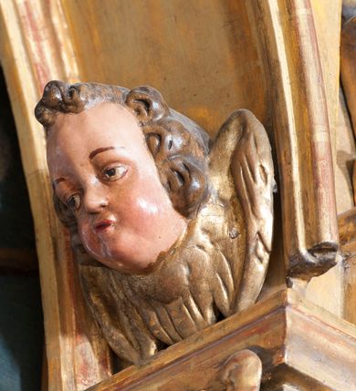 Zdjęcie nr 42: Ołtarz architektoniczny, z wydzieloną predellą, trójosiowy, dwukondygnacyjny ze zwieńczeniem. Predella węższa od nastawy, rozszerzająca się ku górze. Dolna kondygnacja artykułowana kolumnami o trzonach przedzielonych opaską w jednej trzeciej wysokości, zdobionych główkami aniołków, girlandami i dekoracją kandelabrową; kapitele kompozytowe; w osiach zewnętrznych kolumny nadwieszone na konsolach, w osiach wewnętrznych ustawione na postumentach. Kolumny wspierają belkowanie i gzyms występujące nad nimi. W polu środkowym prostokątna nisza zamknięta półkoliście, w niej obraz: Chrzest Chrystusa; w polach bocznych mniejsze nisze prostokątne zamknięte półkoliście, muszlowe, w nich rzeźby: Św. Piotr i Św. Paweł. Górna kondygnacja ujęta kolumnami o kręconych trzonach z dekoracją roślinną i kompozytowych kapitelach, wspierającymi belkowanie i profilowany gzyms. W polu środkowym nisza zamknięta półkoliście w niej obraz: Matka Boska z Dzieciątkiem. Po bokach obrazu rzeźby: Św. Anna (?) i Św. Marcin (?). Dolna i górna kondygnacje flankowane rzeźbionymi, ażurowymi uszakami z motywem herm aniołów. W osiach kolumn dolnej kondygnacji rzeźby: Św. Wojciech i Św. Stanisław. Zwieńczenie w kształcie półkolistego przyczółka wspartego na konsoli wchodzącej w pole górnej kondygnacji. W polu zwieńczenia płaskorzeźbione, półplastyczne przedstawienie Boga Ojca w popiersiu, flankowane wolutami z półpostaciami dwóch uskrzydlonych aniołów. Po bokach w zwieńczeniu, w osiach kolumn górnej kondygnacji, rzeźby uskrzydlonych aniołów.   W szczycie ołtarza na konsoli rzeźba: Św. Michał Archanioł. W przyłuczach nisz na obrazy, ponad niszami na rzeźby, w predelli, na konsolach i postumentach kolumn dolnej kondygnacji oraz na konsoli poniżej zwieńczenia uskrzydlone główki aniołków. Ponadto poniżej nisz, w tle kolumn oraz na belkowaniu płyciny ornamentalne z motywów roślinnych i motywy rautów. Struktura ołtarza, rzeźby i ornamenty złocone, karnacje i włosy polichromowane.  
