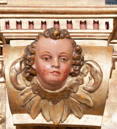 Zdjęcie nr 43: Ołtarz architektoniczny, z wydzieloną predellą, trójosiowy, dwukondygnacyjny ze zwieńczeniem. Predella węższa od nastawy, rozszerzająca się ku górze. Dolna kondygnacja artykułowana kolumnami o trzonach przedzielonych opaską w jednej trzeciej wysokości, zdobionych główkami aniołków, girlandami i dekoracją kandelabrową; kapitele kompozytowe; w osiach zewnętrznych kolumny nadwieszone na konsolach, w osiach wewnętrznych ustawione na postumentach. Kolumny wspierają belkowanie i gzyms występujące nad nimi. W polu środkowym prostokątna nisza zamknięta półkoliście, w niej obraz: Chrzest Chrystusa; w polach bocznych mniejsze nisze prostokątne zamknięte półkoliście, muszlowe, w nich rzeźby: Św. Piotr i Św. Paweł. Górna kondygnacja ujęta kolumnami o kręconych trzonach z dekoracją roślinną i kompozytowych kapitelach, wspierającymi belkowanie i profilowany gzyms. W polu środkowym nisza zamknięta półkoliście w niej obraz: Matka Boska z Dzieciątkiem. Po bokach obrazu rzeźby: Św. Anna (?) i Św. Marcin (?). Dolna i górna kondygnacje flankowane rzeźbionymi, ażurowymi uszakami z motywem herm aniołów. W osiach kolumn dolnej kondygnacji rzeźby: Św. Wojciech i Św. Stanisław. Zwieńczenie w kształcie półkolistego przyczółka wspartego na konsoli wchodzącej w pole górnej kondygnacji. W polu zwieńczenia płaskorzeźbione, półplastyczne przedstawienie Boga Ojca w popiersiu, flankowane wolutami z półpostaciami dwóch uskrzydlonych aniołów. Po bokach w zwieńczeniu, w osiach kolumn górnej kondygnacji, rzeźby uskrzydlonych aniołów.   W szczycie ołtarza na konsoli rzeźba: Św. Michał Archanioł. W przyłuczach nisz na obrazy, ponad niszami na rzeźby, w predelli, na konsolach i postumentach kolumn dolnej kondygnacji oraz na konsoli poniżej zwieńczenia uskrzydlone główki aniołków. Ponadto poniżej nisz, w tle kolumn oraz na belkowaniu płyciny ornamentalne z motywów roślinnych i motywy rautów. Struktura ołtarza, rzeźby i ornamenty złocone, karnacje i włosy polichromowane.  
