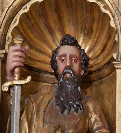 Zdjęcie nr 5: Rzeźba pełnoplastyczna, przyścienna, ścięta z tyłu. Figura zwrócona frontalnie do widza, święty lewą nogę opiera na rzeźbionym fragmencie skały; w prawej ręce unosi zwrócony ostrzem w dół duży miecz, lewą podtrzymuje opartą na biodrze księgę. Twarz pociągła, o głęboko osadzonych, półprzymkniętych oczach, dużym prostym nosie, okolona długą brodą opadającą na pierś. Włosy krótkie, falowane. Święty ubrany w tunikę z długimi rękawami, przepasaną w talii, u dołu obficie drapowaną w równoległe fałdy oraz płaszcz przerzucony przez prawe ramię i przewieszony przez pas na lewym boku. Figura delikatnie poruszona, o niewłaściwych proporcjach anatomicznych. Polichromia naturalistyczna w partiach ciała, szaty złocone, miecz srebrzony.