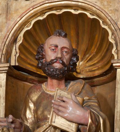 Zdjęcie nr 4: Rzeźba pełnoplastyczna, przyścienna, ścięta z tyłu. Figura zwrócona frontalnie do widza, z głową skierowaną w prawą stronę. Święty prawą nogę opiera na rzeźbionym fragmencie skały; w prawej, wyciągniętej przed siebie ręce trzyma klucze, lewą podtrzymuje przy piersi księgę. Twarz pociągła, o głęboko osadzonych, półprzymkniętych oczach, dużym prostym nosie, okolona brodą. Włosy krótkie, falowane w postaci pukli po bokach i na czubku głowy. Święty ubrany w tunikę z długimi rękawami, przepasaną w talii, u dołu obficie drapowaną w równoległe fałdy, oraz płaszcz przerzucony przez lewe ramię oraz przewieszony przez pas na prawym boku. Rzeźba, delikatnie poruszona, o zaburzonych proporcjach ciała. Polichromia naturalistyczna w partiach ciała, szaty złocone.