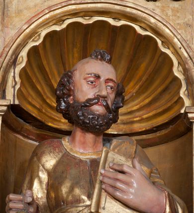 Zdjęcie nr 6: Rzeźba pełnoplastyczna, przyścienna, ścięta z tyłu. Figura zwrócona frontalnie do widza, z głową skierowaną w prawą stronę. Święty prawą nogę opiera na rzeźbionym fragmencie skały; w prawej, wyciągniętej przed siebie ręce trzyma klucze, lewą podtrzymuje przy piersi księgę. Twarz pociągła, o głęboko osadzonych, półprzymkniętych oczach, dużym prostym nosie, okolona brodą. Włosy krótkie, falowane w postaci pukli po bokach i na czubku głowy. Święty ubrany w tunikę z długimi rękawami, przepasaną w talii, u dołu obficie drapowaną w równoległe fałdy, oraz płaszcz przerzucony przez lewe ramię oraz przewieszony przez pas na prawym boku. Rzeźba, delikatnie poruszona, o zaburzonych proporcjach ciała. Polichromia naturalistyczna w partiach ciała, szaty złocone.