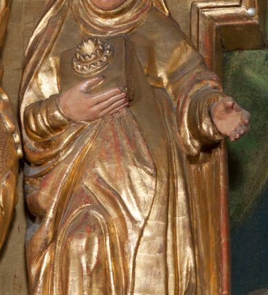 Zdjęcie nr 2: Rzeźba pełnoplastyczna, przyścienna, ścięta z tyłu. Święta ukazana frontalnie, w lekkim kontrapoście, z prawą nogą ugiętą w kolanie i wysuniętą stopą. Ręce ugięte w łokciach. Prawą dłonią przyciska przez połę płaszcza nierozpoznany przedmiot; lewą wyciąga przed siebie. Twarz okrągła, pełna, o rysach dojrzałej kobiety, oczy zwrócone ku górze. Ubrana w przewiązaną w pasie tunikę oraz płaszcz podwinięty pod prawą ręką i odsłaniający prawą nogę, na głowie długi welon z podwiką. Polichromia naturalistyczna w partiach ciała, szaty złocone.