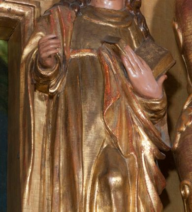 Zdjęcie nr 2: Rzeźba pełnoplastyczna, przyścienna, ścięta z tyłu. Święty, ukazany frontalnie, w lekkim kontrapoście, z lewą nogą ugiętą w kolanie i wysuniętą stopą. Lewą ręką przytrzymuje na piersi księgę, prawą wyciąga przed siebie. Twarz okrągła, pełna, o młodzieńczych rysach, oczy zwrócone ku górze. Włosy długie, falowane, opadają na ramiona i plecy. Ubrany w tunikę oraz płaszcz przerzucony przez prawe ramie i zawinięty na lewym boku. Przy lewej nodze niewielka półpostać mężczyzny w stożkowym nakryciu głowy. Polichromia naturalistyczna w partiach ciała, szaty złocone.