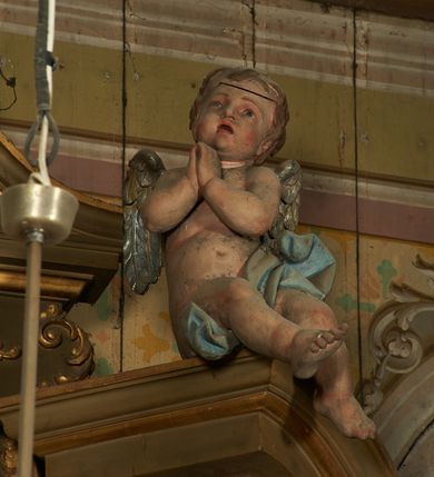 Zdjęcie nr 7: Nastawa ołtarzowa architektoniczna, jednoosiowa, jednokondygnacyjna ze zwieńczeniem. Ołtarz drewniany, prostopadłościenny, mensa drewniana. Nastawa ustawiona na cokole zakończonym gzymsem z motywem wolego oka, dekorowanym płycinami z kartuszami, z wyodrębnionym po środku tabernakulum flankowanym pilastrami z konsolami i kampanulami. Drzwiczki tabernakulum w formie stojącego prostokąta zamkniętego łukiem półkolistym z przedstawieniem kielicha z hostią w glorii. Nastawa ujęta parą zdwojonych filarów ustawionych pod kątem, o kanelowanych trzonach i kapitelach kompozytowych dźwigających fragmenty przerwanego belkowania dekorowanego wolim okiem oraz ćwierćkolistego, przerwanego przyczółka, na których siedzi para puttów. Na tle filarów, po zewnętrznej stronie ustawione są figury biskupów. W polu środkowym wnęka w formie stojącego prostokąta zamkniętego łukiem półkolistym nadwieszonym, ujęta grubą ramą dekorowaną wstęgą przeplataną z pąkami kwiatów, zwieńczona kartuszem; w polu figura Chrystusa Ukrzyżowanego na czerwonym tle. W przyłuczach dwie uskrzydlone główki anielskie. Zwieńczenie w formie stojącego prostokąta ujętego spływami wolutowymi, zamknięte fragmentem gzymsu, na którym znajduje się szczyt utworzony z przeciwstawnie zwróconych wolut z anthemionem. W polu zwieńczenia obraz w formie stojącego prostokąta z zaokrąglonymi górnymi narożami z przedstawieniem Matki Boskiej Bolesnej, ujęty profilowaną ramą. Ponad nim wić roślinna. Struktura ołtarza malowana na kolor jasnobrązowy, profile i ornamenty złocone.
