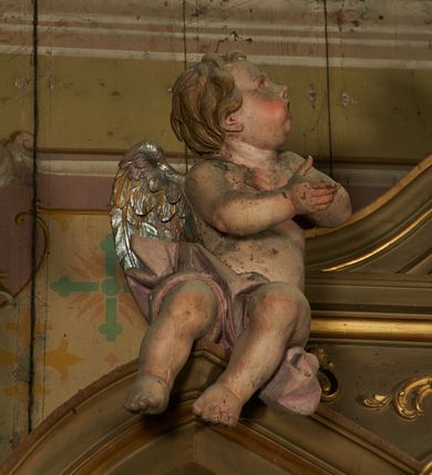 Zdjęcie nr 6: Nastawa ołtarzowa architektoniczna, jednoosiowa, jednokondygnacyjna ze zwieńczeniem. Ołtarz drewniany, prostopadłościenny, mensa drewniana. Nastawa ustawiona na cokole zakończonym gzymsem z motywem wolego oka, dekorowanym płycinami z kartuszami, z wyodrębnionym po środku tabernakulum flankowanym pilastrami z konsolami i kampanulami. Drzwiczki tabernakulum w formie stojącego prostokąta zamkniętego łukiem półkolistym z przedstawieniem kielicha z hostią w glorii. Nastawa ujęta parą zdwojonych filarów ustawionych pod kątem, o kanelowanych trzonach i kapitelach kompozytowych dźwigających fragmenty przerwanego belkowania dekorowanego wolim okiem oraz ćwierćkolistego, przerwanego przyczółka, na których siedzi para puttów. Na tle filarów, po zewnętrznej stronie ustawione są figury biskupów. W polu środkowym wnęka w formie stojącego prostokąta zamkniętego łukiem półkolistym nadwieszonym, ujęta grubą ramą dekorowaną wstęgą przeplataną z pąkami kwiatów, zwieńczona kartuszem; w polu figura Chrystusa Ukrzyżowanego na czerwonym tle. W przyłuczach dwie uskrzydlone główki anielskie. Zwieńczenie w formie stojącego prostokąta ujętego spływami wolutowymi, zamknięte fragmentem gzymsu, na którym znajduje się szczyt utworzony z przeciwstawnie zwróconych wolut z anthemionem. W polu zwieńczenia obraz w formie stojącego prostokąta z zaokrąglonymi górnymi narożami z przedstawieniem Matki Boskiej Bolesnej, ujęty profilowaną ramą. Ponad nim wić roślinna. Struktura ołtarza malowana na kolor jasnobrązowy, profile i ornamenty złocone.
