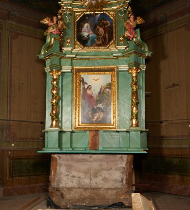 Zdjęcie nr 2: Nastawa architektoniczna, dwukondygnacyjna, jednoosiowa z bramkami. Ołtarz kamienny, w drewnianej prostopadłościennej obudowie, z drewnianą mensą. Na niej ustawione tabernakulum. Pierwsza kondygnacja na cokole z wyodrębnionymi dwoma prostopadłościanami, dekorowanym ornamentem roślinnym; ujęta parą kolumn o kapitelach kompozytowych oraz skręconych trzonach dekorowanych winną latoroślą. Podpory oraz konsole podtrzymują pełne belkowanie wyłamane pod kątem na ich osi, z architrawem przerwanym nad polem środkowym, oraz fragmenty falistego, przerwanego przyczółka, na którym znajdują się dwie siedzące figury aniołów. Fryz dekorowany rozetami, ornamentem roślinnym i kartuszem. W polu środkowym wnęka w formie stojącego prostokąta ujęta ramą dekorowaną płaskorzeźbionym wieńcem, w niej obraz Trójcy Świętej w osobnej ramie zdobionej ornamentem roślinnym. Druga kondygnacja na niskim cokole z wyodrębnionymi prostopadłościanami, flankowana parą pilastrów zakończonych konsolami podtrzymującymi belkowanie, wyłamane na ich osi. Całe pole wypełnia wnęka w formie  prostokąta zbliżonego do kwadratu ujęta ramą, wewnątrz obraz przedstawiający pokłon pasterzy w formie leżącego prostokąta o świętych narożach, w ramie dekorowanej ornamentem roślinnym, w narożach wnęki rozety. Na osi pilastrów, na belkowaniu muszle. Całość zakończona medalionem z gołębicą Ducha Świętego, otoczonego obłokami, w glorii promienistej. Obie kondygnacje ujęte uszami utworzonymi z ażurowego akantu. Bramki zamknięte trójbocznie z przejściami w formie stojącego prostokąta zamkniętego łukiem półkolistym nadwieszonym w ramie. Na bramkach ustawione figury św. Wojciecha i św. Stanisława. Struktura polichromowana w sposób imitujący jasnozielony marmur, profile, kolumny i ornamentyka złocone, obłoki srebrzone, winna latorośl laserowana. 