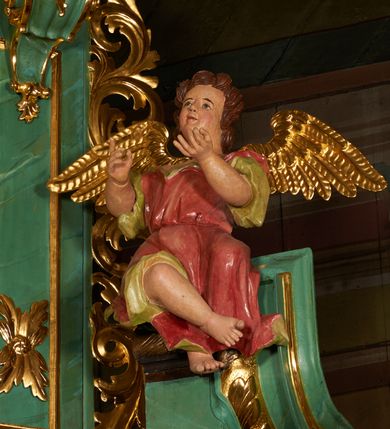 Zdjęcie nr 7: Nastawa architektoniczna, dwukondygnacyjna, jednoosiowa z bramkami. Ołtarz kamienny, w drewnianej prostopadłościennej obudowie, z drewnianą mensą. Na niej ustawione tabernakulum. Pierwsza kondygnacja na cokole z wyodrębnionymi dwoma prostopadłościanami, dekorowanym ornamentem roślinnym; ujęta parą kolumn o kapitelach kompozytowych oraz skręconych trzonach dekorowanych winną latoroślą. Podpory oraz konsole podtrzymują pełne belkowanie wyłamane pod kątem na ich osi, z architrawem przerwanym nad polem środkowym, oraz fragmenty falistego, przerwanego przyczółka, na którym znajdują się dwie siedzące figury aniołów. Fryz dekorowany rozetami, ornamentem roślinnym i kartuszem. W polu środkowym wnęka w formie stojącego prostokąta ujęta ramą dekorowaną płaskorzeźbionym wieńcem, w niej obraz Trójcy Świętej w osobnej ramie zdobionej ornamentem roślinnym. Druga kondygnacja na niskim cokole z wyodrębnionymi prostopadłościanami, flankowana parą pilastrów zakończonych konsolami podtrzymującymi belkowanie, wyłamane na ich osi. Całe pole wypełnia wnęka w formie  prostokąta zbliżonego do kwadratu ujęta ramą, wewnątrz obraz przedstawiający pokłon pasterzy w formie leżącego prostokąta o świętych narożach, w ramie dekorowanej ornamentem roślinnym, w narożach wnęki rozety. Na osi pilastrów, na belkowaniu muszle. Całość zakończona medalionem z gołębicą Ducha Świętego, otoczonego obłokami, w glorii promienistej. Obie kondygnacje ujęte uszami utworzonymi z ażurowego akantu. Bramki zamknięte trójbocznie z przejściami w formie stojącego prostokąta zamkniętego łukiem półkolistym nadwieszonym w ramie. Na bramkach ustawione figury św. Wojciecha i św. Stanisława. Struktura polichromowana w sposób imitujący jasnozielony marmur, profile, kolumny i ornamentyka złocone, obłoki srebrzone, winna latorośl laserowana. 