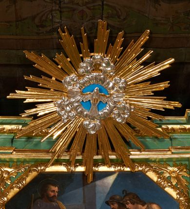 Zdjęcie nr 9: Nastawa architektoniczna, dwukondygnacyjna, jednoosiowa z bramkami. Ołtarz kamienny, w drewnianej prostopadłościennej obudowie, z drewnianą mensą. Na niej ustawione tabernakulum. Pierwsza kondygnacja na cokole z wyodrębnionymi dwoma prostopadłościanami, dekorowanym ornamentem roślinnym; ujęta parą kolumn o kapitelach kompozytowych oraz skręconych trzonach dekorowanych winną latoroślą. Podpory oraz konsole podtrzymują pełne belkowanie wyłamane pod kątem na ich osi, z architrawem przerwanym nad polem środkowym, oraz fragmenty falistego, przerwanego przyczółka, na którym znajdują się dwie siedzące figury aniołów. Fryz dekorowany rozetami, ornamentem roślinnym i kartuszem. W polu środkowym wnęka w formie stojącego prostokąta ujęta ramą dekorowaną płaskorzeźbionym wieńcem, w niej obraz Trójcy Świętej w osobnej ramie zdobionej ornamentem roślinnym. Druga kondygnacja na niskim cokole z wyodrębnionymi prostopadłościanami, flankowana parą pilastrów zakończonych konsolami podtrzymującymi belkowanie, wyłamane na ich osi. Całe pole wypełnia wnęka w formie  prostokąta zbliżonego do kwadratu ujęta ramą, wewnątrz obraz przedstawiający pokłon pasterzy w formie leżącego prostokąta o świętych narożach, w ramie dekorowanej ornamentem roślinnym, w narożach wnęki rozety. Na osi pilastrów, na belkowaniu muszle. Całość zakończona medalionem z gołębicą Ducha Świętego, otoczonego obłokami, w glorii promienistej. Obie kondygnacje ujęte uszami utworzonymi z ażurowego akantu. Bramki zamknięte trójbocznie z przejściami w formie stojącego prostokąta zamkniętego łukiem półkolistym nadwieszonym w ramie. Na bramkach ustawione figury św. Wojciecha i św. Stanisława. Struktura polichromowana w sposób imitujący jasnozielony marmur, profile, kolumny i ornamentyka złocone, obłoki srebrzone, winna latorośl laserowana. 