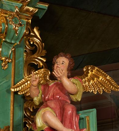 Zdjęcie nr 8: Nastawa architektoniczna, dwukondygnacyjna, jednoosiowa z bramkami. Ołtarz kamienny, w drewnianej prostopadłościennej obudowie, z drewnianą mensą. Na niej ustawione tabernakulum. Pierwsza kondygnacja na cokole z wyodrębnionymi dwoma prostopadłościanami, dekorowanym ornamentem roślinnym; ujęta parą kolumn o kapitelach kompozytowych oraz skręconych trzonach dekorowanych winną latoroślą. Podpory oraz konsole podtrzymują pełne belkowanie wyłamane pod kątem na ich osi, z architrawem przerwanym nad polem środkowym, oraz fragmenty falistego, przerwanego przyczółka, na którym znajdują się dwie siedzące figury aniołów. Fryz dekorowany rozetami, ornamentem roślinnym i kartuszem. W polu środkowym wnęka w formie stojącego prostokąta ujęta ramą dekorowaną płaskorzeźbionym wieńcem, w niej obraz Trójcy Świętej w osobnej ramie zdobionej ornamentem roślinnym. Druga kondygnacja na niskim cokole z wyodrębnionymi prostopadłościanami, flankowana parą pilastrów zakończonych konsolami podtrzymującymi belkowanie, wyłamane na ich osi. Całe pole wypełnia wnęka w formie  prostokąta zbliżonego do kwadratu ujęta ramą, wewnątrz obraz przedstawiający pokłon pasterzy w formie leżącego prostokąta o świętych narożach, w ramie dekorowanej ornamentem roślinnym, w narożach wnęki rozety. Na osi pilastrów, na belkowaniu muszle. Całość zakończona medalionem z gołębicą Ducha Świętego, otoczonego obłokami, w glorii promienistej. Obie kondygnacje ujęte uszami utworzonymi z ażurowego akantu. Bramki zamknięte trójbocznie z przejściami w formie stojącego prostokąta zamkniętego łukiem półkolistym nadwieszonym w ramie. Na bramkach ustawione figury św. Wojciecha i św. Stanisława. Struktura polichromowana w sposób imitujący jasnozielony marmur, profile, kolumny i ornamentyka złocone, obłoki srebrzone, winna latorośl laserowana. 