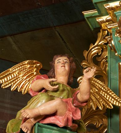 Zdjęcie nr 6: Nastawa architektoniczna, dwukondygnacyjna, jednoosiowa z bramkami. Ołtarz kamienny, w drewnianej prostopadłościennej obudowie, z drewnianą mensą. Na niej ustawione tabernakulum. Pierwsza kondygnacja na cokole z wyodrębnionymi dwoma prostopadłościanami, dekorowanym ornamentem roślinnym; ujęta parą kolumn o kapitelach kompozytowych oraz skręconych trzonach dekorowanych winną latoroślą. Podpory oraz konsole podtrzymują pełne belkowanie wyłamane pod kątem na ich osi, z architrawem przerwanym nad polem środkowym, oraz fragmenty falistego, przerwanego przyczółka, na którym znajdują się dwie siedzące figury aniołów. Fryz dekorowany rozetami, ornamentem roślinnym i kartuszem. W polu środkowym wnęka w formie stojącego prostokąta ujęta ramą dekorowaną płaskorzeźbionym wieńcem, w niej obraz Trójcy Świętej w osobnej ramie zdobionej ornamentem roślinnym. Druga kondygnacja na niskim cokole z wyodrębnionymi prostopadłościanami, flankowana parą pilastrów zakończonych konsolami podtrzymującymi belkowanie, wyłamane na ich osi. Całe pole wypełnia wnęka w formie  prostokąta zbliżonego do kwadratu ujęta ramą, wewnątrz obraz przedstawiający pokłon pasterzy w formie leżącego prostokąta o świętych narożach, w ramie dekorowanej ornamentem roślinnym, w narożach wnęki rozety. Na osi pilastrów, na belkowaniu muszle. Całość zakończona medalionem z gołębicą Ducha Świętego, otoczonego obłokami, w glorii promienistej. Obie kondygnacje ujęte uszami utworzonymi z ażurowego akantu. Bramki zamknięte trójbocznie z przejściami w formie stojącego prostokąta zamkniętego łukiem półkolistym nadwieszonym w ramie. Na bramkach ustawione figury św. Wojciecha i św. Stanisława. Struktura polichromowana w sposób imitujący jasnozielony marmur, profile, kolumny i ornamentyka złocone, obłoki srebrzone, winna latorośl laserowana. 