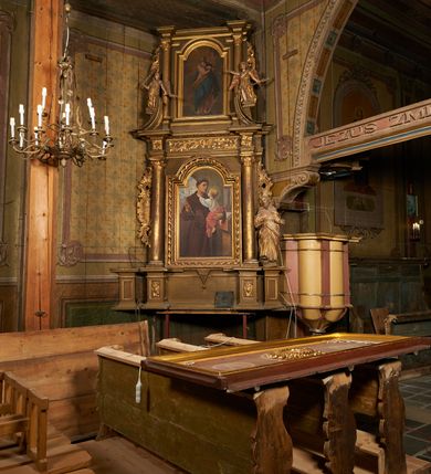 Zdjęcie nr 2: Nastawa architektoniczna, jednoosiowa, dwukondygnacyjna. Pierwsza kondygnacja ustawiona na cokole dekorowanym płycinami i kartuszami, z wyodrębnioną parą prostopadłościanów oraz zewnętrznymi cokołami, flankowana parą kolumn o kapitelach kompozytowych dźwigających pełne belkowanie, wyłamane na ich osi, z architrawem przerwanym polem obrazowym, oraz fryzem dekorowanym akantem i rozetami. Na belkowaniu fragmenty przerwanego przyczółka, na którym znajduje się para cokołów z figurami aniołów. Pole środkowe w całości wypełnione wnęką w formie stojącego prostokąta zamkniętego łukiem półkolistym nadwieszonym, ujętą ramą dekorowaną wstęgą, z obrazem św. Antoniego Padewskiego w osobnej, profilowanej ramie. Kondygnacja ujęta uszami utworzonymi z ażurowego rocaille&#039;u. Na jednym z zewnętrznych cokołów stoi figura niezidentyfikowanego świętego. Druga kondygnacja ustawiona na niskim cokole z wyodrębnionymi dwoma postumentami, ujęta parą kolumn dźwigających pełne belkowanie z architrawem i fryzem przerwanym nad polem. W polu wnęka w formie stojącego prostokąta zamkniętego łukiem półkolistym nadwieszonym, ujęta profilowaną ramą, z obrazem Najświętszej Marii Panny Niepokalanie Poczętej. Druga kondygnacja ujęta uszami utworzonymi z ażurowego akantu. Struktura polichromowana w kolorze jasnobrązowym, profile, ornamentyka i kolumny złocone. 