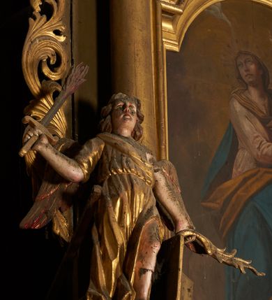 Zdjęcie nr 3: Nastawa architektoniczna, jednoosiowa, dwukondygnacyjna. Pierwsza kondygnacja ustawiona na cokole dekorowanym płycinami i kartuszami, z wyodrębnioną parą prostopadłościanów oraz zewnętrznymi cokołami, flankowana parą kolumn o kapitelach kompozytowych dźwigających pełne belkowanie, wyłamane na ich osi, z architrawem przerwanym polem obrazowym, oraz fryzem dekorowanym akantem i rozetami. Na belkowaniu fragmenty przerwanego przyczółka, na którym znajduje się para cokołów z figurami aniołów. Pole środkowe w całości wypełnione wnęką w formie stojącego prostokąta zamkniętego łukiem półkolistym nadwieszonym, ujętą ramą dekorowaną wstęgą, z obrazem św. Antoniego Padewskiego w osobnej, profilowanej ramie. Kondygnacja ujęta uszami utworzonymi z ażurowego rocaille&#039;u. Na jednym z zewnętrznych cokołów stoi figura niezidentyfikowanego świętego. Druga kondygnacja ustawiona na niskim cokole z wyodrębnionymi dwoma postumentami, ujęta parą kolumn dźwigających pełne belkowanie z architrawem i fryzem przerwanym nad polem. W polu wnęka w formie stojącego prostokąta zamkniętego łukiem półkolistym nadwieszonym, ujęta profilowaną ramą, z obrazem Najświętszej Marii Panny Niepokalanie Poczętej. Druga kondygnacja ujęta uszami utworzonymi z ażurowego akantu. Struktura polichromowana w kolorze jasnobrązowym, profile, ornamentyka i kolumny złocone. 