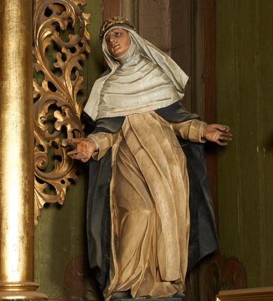 Zdjęcie nr 8: Nastawa architektoniczna, dwukondygnacyjna, jednoosiowa z bramkami. Ołtarz prostopadłościenny, drewniany, w jego polu malowane na drewnie przedstawienie Chrystusa w grobie; mensa drewniana. Pierwsza kondygnacja na niewysokim cokole, flankowana wewnętrzną parą pilastrów skierowaną pod kątem do wewnątrz oraz parą pilastrów i stojącą przed nimi parą kolumn zwróconymi pod kątem na zewnątrz. Podpory dźwigają pełne belkowanie, wyłamane na ich osi, w partii wewnętrznych pilastrów podtrzymywane przez konsole, nad kolumnami fragmenty przerwanego przyczółka zwróconego do wewnątrz, na którym znajduje się para puttów. W polu środkowym wnęka w formie stojącego prostokąta zamkniętego łukiem półkolistym nadwieszonym, ujęta profilowaną ramą z obrazem Matki Boskiej z Dzieciątkiem. W partii trzonów wewnętrznych pilastrów gabloty na wota. Nad obrazem, w partii belkowania kartusz utworzony z muszli z gołębicą Ducha Świętego w glorii promienistej. Kondygnacja flankowana uszami utworzonymi z suchego akantu. Druga kondygnacja w formie zbliżonej do kwadratu, ujęta parą filarów zwróconych pod kątem do wewnątrz, dźwigających belkowanie, wyłamanego na ich osi, niepełne nad polem. W polu środkowym obraz św. Mikołaja w formie zbliżonej do kwadratu, ujęty profilowaną ramą. Całość zakończona okiem Opatrzności na tle obłoków, w glorii promienistej. Bramki w formie arkad opartych na węgarach, zakończonych niskimi cokołami z figurami św. Dominika i św. Katarzyny Sieneńskiej. Struktura ołtarza malowana w kolorze brązowym, detale ciemnobrązowym, ornamentyka, profile i kolumny złocone.