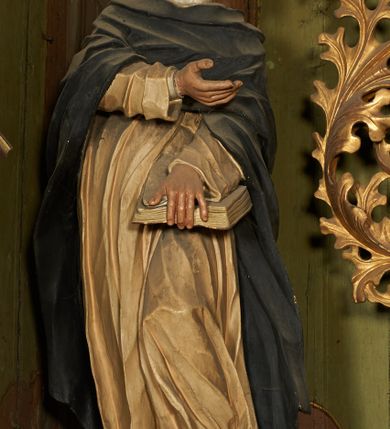 Zdjęcie nr 7: Nastawa architektoniczna, dwukondygnacyjna, jednoosiowa z bramkami. Ołtarz prostopadłościenny, drewniany, w jego polu malowane na drewnie przedstawienie Chrystusa w grobie; mensa drewniana. Pierwsza kondygnacja na niewysokim cokole, flankowana wewnętrzną parą pilastrów skierowaną pod kątem do wewnątrz oraz parą pilastrów i stojącą przed nimi parą kolumn zwróconymi pod kątem na zewnątrz. Podpory dźwigają pełne belkowanie, wyłamane na ich osi, w partii wewnętrznych pilastrów podtrzymywane przez konsole, nad kolumnami fragmenty przerwanego przyczółka zwróconego do wewnątrz, na którym znajduje się para puttów. W polu środkowym wnęka w formie stojącego prostokąta zamkniętego łukiem półkolistym nadwieszonym, ujęta profilowaną ramą z obrazem Matki Boskiej z Dzieciątkiem. W partii trzonów wewnętrznych pilastrów gabloty na wota. Nad obrazem, w partii belkowania kartusz utworzony z muszli z gołębicą Ducha Świętego w glorii promienistej. Kondygnacja flankowana uszami utworzonymi z suchego akantu. Druga kondygnacja w formie zbliżonej do kwadratu, ujęta parą filarów zwróconych pod kątem do wewnątrz, dźwigających belkowanie, wyłamanego na ich osi, niepełne nad polem. W polu środkowym obraz św. Mikołaja w formie zbliżonej do kwadratu, ujęty profilowaną ramą. Całość zakończona okiem Opatrzności na tle obłoków, w glorii promienistej. Bramki w formie arkad opartych na węgarach, zakończonych niskimi cokołami z figurami św. Dominika i św. Katarzyny Sieneńskiej. Struktura ołtarza malowana w kolorze brązowym, detale ciemnobrązowym, ornamentyka, profile i kolumny złocone.