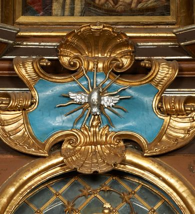 Zdjęcie nr 4: Nastawa architektoniczna, dwukondygnacyjna, jednoosiowa z bramkami. Ołtarz prostopadłościenny, drewniany, w jego polu malowane na drewnie przedstawienie Chrystusa w grobie; mensa drewniana. Pierwsza kondygnacja na niewysokim cokole, flankowana wewnętrzną parą pilastrów skierowaną pod kątem do wewnątrz oraz parą pilastrów i stojącą przed nimi parą kolumn zwróconymi pod kątem na zewnątrz. Podpory dźwigają pełne belkowanie, wyłamane na ich osi, w partii wewnętrznych pilastrów podtrzymywane przez konsole, nad kolumnami fragmenty przerwanego przyczółka zwróconego do wewnątrz, na którym znajduje się para puttów. W polu środkowym wnęka w formie stojącego prostokąta zamkniętego łukiem półkolistym nadwieszonym, ujęta profilowaną ramą z obrazem Matki Boskiej z Dzieciątkiem. W partii trzonów wewnętrznych pilastrów gabloty na wota. Nad obrazem, w partii belkowania kartusz utworzony z muszli z gołębicą Ducha Świętego w glorii promienistej. Kondygnacja flankowana uszami utworzonymi z suchego akantu. Druga kondygnacja w formie zbliżonej do kwadratu, ujęta parą filarów zwróconych pod kątem do wewnątrz, dźwigających belkowanie, wyłamanego na ich osi, niepełne nad polem. W polu środkowym obraz św. Mikołaja w formie zbliżonej do kwadratu, ujęty profilowaną ramą. Całość zakończona okiem Opatrzności na tle obłoków, w glorii promienistej. Bramki w formie arkad opartych na węgarach, zakończonych niskimi cokołami z figurami św. Dominika i św. Katarzyny Sieneńskiej. Struktura ołtarza malowana w kolorze brązowym, detale ciemnobrązowym, ornamentyka, profile i kolumny złocone.