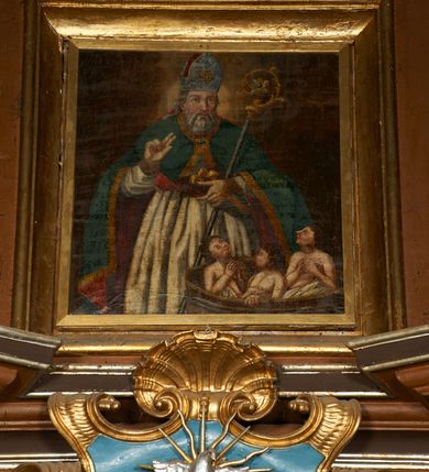 Zdjęcie nr 5: Nastawa architektoniczna, dwukondygnacyjna, jednoosiowa z bramkami. Ołtarz prostopadłościenny, drewniany, w jego polu malowane na drewnie przedstawienie Chrystusa w grobie; mensa drewniana. Pierwsza kondygnacja na niewysokim cokole, flankowana wewnętrzną parą pilastrów skierowaną pod kątem do wewnątrz oraz parą pilastrów i stojącą przed nimi parą kolumn zwróconymi pod kątem na zewnątrz. Podpory dźwigają pełne belkowanie, wyłamane na ich osi, w partii wewnętrznych pilastrów podtrzymywane przez konsole, nad kolumnami fragmenty przerwanego przyczółka zwróconego do wewnątrz, na którym znajduje się para puttów. W polu środkowym wnęka w formie stojącego prostokąta zamkniętego łukiem półkolistym nadwieszonym, ujęta profilowaną ramą z obrazem Matki Boskiej z Dzieciątkiem. W partii trzonów wewnętrznych pilastrów gabloty na wota. Nad obrazem, w partii belkowania kartusz utworzony z muszli z gołębicą Ducha Świętego w glorii promienistej. Kondygnacja flankowana uszami utworzonymi z suchego akantu. Druga kondygnacja w formie zbliżonej do kwadratu, ujęta parą filarów zwróconych pod kątem do wewnątrz, dźwigających belkowanie, wyłamanego na ich osi, niepełne nad polem. W polu środkowym obraz św. Mikołaja w formie zbliżonej do kwadratu, ujęty profilowaną ramą. Całość zakończona okiem Opatrzności na tle obłoków, w glorii promienistej. Bramki w formie arkad opartych na węgarach, zakończonych niskimi cokołami z figurami św. Dominika i św. Katarzyny Sieneńskiej. Struktura ołtarza malowana w kolorze brązowym, detale ciemnobrązowym, ornamentyka, profile i kolumny złocone.