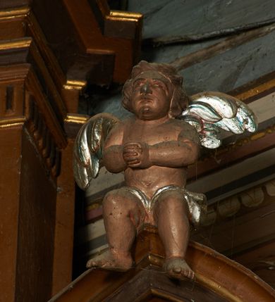 Zdjęcie nr 6: Nastawa architektoniczna, dwukondygnacyjna, jednoosiowa z bramkami. Ołtarz prostopadłościenny, drewniany, w jego polu malowane na drewnie przedstawienie Chrystusa w grobie; mensa drewniana. Pierwsza kondygnacja na niewysokim cokole, flankowana wewnętrzną parą pilastrów skierowaną pod kątem do wewnątrz oraz parą pilastrów i stojącą przed nimi parą kolumn zwróconymi pod kątem na zewnątrz. Podpory dźwigają pełne belkowanie, wyłamane na ich osi, w partii wewnętrznych pilastrów podtrzymywane przez konsole, nad kolumnami fragmenty przerwanego przyczółka zwróconego do wewnątrz, na którym znajduje się para puttów. W polu środkowym wnęka w formie stojącego prostokąta zamkniętego łukiem półkolistym nadwieszonym, ujęta profilowaną ramą z obrazem Matki Boskiej z Dzieciątkiem. W partii trzonów wewnętrznych pilastrów gabloty na wota. Nad obrazem, w partii belkowania kartusz utworzony z muszli z gołębicą Ducha Świętego w glorii promienistej. Kondygnacja flankowana uszami utworzonymi z suchego akantu. Druga kondygnacja w formie zbliżonej do kwadratu, ujęta parą filarów zwróconych pod kątem do wewnątrz, dźwigających belkowanie, wyłamanego na ich osi, niepełne nad polem. W polu środkowym obraz św. Mikołaja w formie zbliżonej do kwadratu, ujęty profilowaną ramą. Całość zakończona okiem Opatrzności na tle obłoków, w glorii promienistej. Bramki w formie arkad opartych na węgarach, zakończonych niskimi cokołami z figurami św. Dominika i św. Katarzyny Sieneńskiej. Struktura ołtarza malowana w kolorze brązowym, detale ciemnobrązowym, ornamentyka, profile i kolumny złocone.