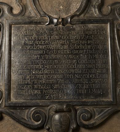 Zdjęcie nr 1: Tablica epitafijna w kształcie leżącego prostokąta, ujęta ramą, flankowana wolutowymi uszakami przechodzącymi w spływy wolutowe. U góry pozostałości po owalnym medalionie w kartuszu; u dołu kartusz z herbem Pilawa, z inicjałami „AT / W” i „Z / W”, ujęty antytetycznie zwróconymi wolutami. W polu tablicy inskrypcja: „D[EO] O[PTIMO] M[AXIMO] / Dopędziwszy szczęśliwie kresu smiertelnego / pełen cnot, y postępków godnych życia swego /  Tu cny mąż Andrzey z Werby Werbski iest złożony / W Woiewodztwie Wołynskim szlachetnie zrodzony / Wieczny pamieci godzien dla swoiey ludzkosci / znamienitey y wielkiey v wszystkich milości / y zyciem, y poboznym zerciem godzien sławy / maż zaprawde herbowney godzien swey Pilay / któremu Magdalena Lyszkowska z dziatkami / zlany ach serdecznemi ten nagrobek łzami / wystawiła w potomny znak affektu swego / wieczney w Bogu swiatłosci / życząc duszy iego / Vmarł roku panskiego 1666 dnia 1 maia / żył lat 46”. 

