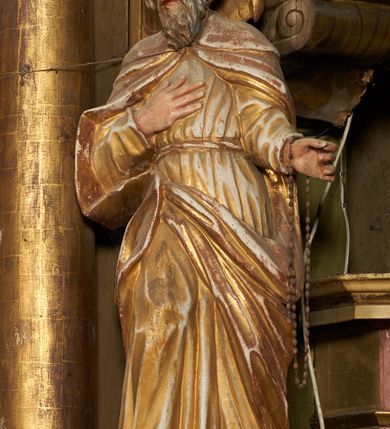 Zdjęcie nr 3: Figura drążona z tyłu, ustawiona na podstawie na nieregularnym planie. Święty ukazany frontalnie, z pochyloną głową skierowaną w prawo, prawa noga oparta na postumencie. Lewa ręka ugięta, wyciągnięta w bok, prawa złożona na piersi. Twarz ma podłużną, o wąskich, migdałowatych oczach, dużym nosie i wąskich, rozchylonych ustach, okoloną falowaną brodą oraz krótkimi włosami z grzywką nad czołem. Święty ubrany w złoconą, przylegającą do ciała, fałdowaną tunikę, przepasaną w talii oraz złocony płaszcz zapięty na piersi, opadający na ramiona z zarzuconą połą na prawą nogę. Polichromia ciała naturalistyczna.
