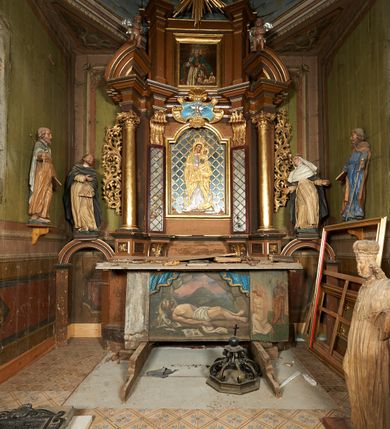 Zdjęcie nr 5: Figura drążona z tyłu, ustawiona na niewielkim postumencie. Święty ukazany frontalnie, pochylony w lewo, z uniesioną głową, w silnym kontrapoście. Lewą ręką przytrzymuje z przodu, na udzie księgę, prawą ugiętą, kieruje w lewo. Twarz ma szczupłą, o głęboko osadzonych, dużych oczach, skierowanych w górę, dużym nosie oraz wąskich, rozchylonych ustach. Twarz okolona jest krótką brodą oraz krótkimi włosami, na głowie tonsura. Święty ubrany w obficie fałdowany, biały habit dominikański oraz czarny płaszcz z kapturem. Polichromia ciała naturalistyczna.