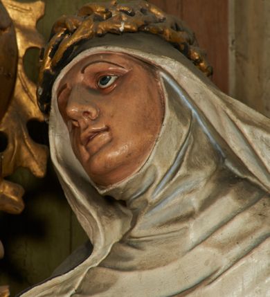 Zdjęcie nr 4: Figura drążona z tyłu, ustawiona na niskiej podstawie. Święta ukazana jest frontalnie, pochylona w prawo, w kontrapoście, z rozłożonymi na boki rękami. Twarz ma pociągłą, o dużych, migdałowatych oczach, dużym nosie i niewielkich, rozchylonych ustach. Ubrana jest w biały habit dominikański ze szkaplerzem, czarny płaszcz opadający na ramiona i plecy oraz biały welon, wokół twarzy ma podwikę, na głowie złoconą koronę cierniową. Polichromia ciała naturalistyczna. 
