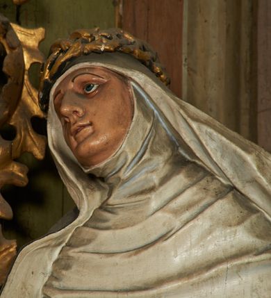 Zdjęcie nr 3: Figura drążona z tyłu, ustawiona na niskiej podstawie. Święta ukazana jest frontalnie, pochylona w prawo, w kontrapoście, z rozłożonymi na boki rękami. Twarz ma pociągłą, o dużych, migdałowatych oczach, dużym nosie i niewielkich, rozchylonych ustach. Ubrana jest w biały habit dominikański ze szkaplerzem, czarny płaszcz opadający na ramiona i plecy oraz biały welon, wokół twarzy ma podwikę, na głowie złoconą koronę cierniową. Polichromia ciała naturalistyczna. 
