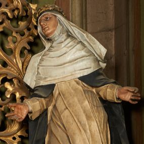Zdjęcie nr 1: Figura drążona z tyłu, ustawiona na niskiej podstawie. Święta ukazana jest frontalnie, pochylona w prawo, w kontrapoście, z rozłożonymi na boki rękami. Twarz ma pociągłą, o dużych, migdałowatych oczach, dużym nosie i niewielkich, rozchylonych ustach. Ubrana jest w biały habit dominikański ze szkaplerzem, czarny płaszcz opadający na ramiona i plecy oraz biały welon, wokół twarzy ma podwikę, na głowie złoconą koronę cierniową. Polichromia ciała naturalistyczna. 
