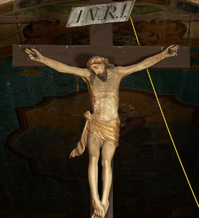 Zdjęcie nr 1: Pełnoplastyczna figura Chrystusa umarłego przybita trzema gwoździami do krzyża o prostym zakończeniu ramion. Ciało w delikatnym zwisie o horyzontalnie rozłożonych ramionach, głowa opadająca na praw bark, nogi lekko ugięte w kolanach, stopy skrzyżowane w układzie prawa na lewą. Chrystus ma pociągłą twarz, o głęboko osadzonych, zamkniętych oczach, długim, wąskim nosie i ustach o opadających kącikach, okoloną falowaną, trójkątną brodą oraz skręconymi w rurkowate pukle włosami. Na głowie ma złoconą koronę cierniową. Ciało szczupłe, wydłużone, o guzowato rzeźbionych mięśniach i żebrach klatki piersiowej oraz wygiętych stopach z podkreślonymi ścięgnami. Perizonium złocone, krótkie, ściśle przylegające do ciała, zawiązane na prawym boku, z lekko rozwianym zwisem tkaniny. Polichromia ciała naturalistyczna. 
U szczytu pionowej belki krzyża tabliczka z malowanym napisem „I.N.R.I.”, pod stopami Chrystusa przybite do krzyża wota.
