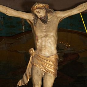 Zdjęcie nr 1: Pełnoplastyczna figura Chrystusa umarłego przybita trzema gwoździami do krzyża o prostym zakończeniu ramion. Ciało w delikatnym zwisie o horyzontalnie rozłożonych ramionach, głowa opadająca na praw bark, nogi lekko ugięte w kolanach, stopy skrzyżowane w układzie prawa na lewą. Chrystus ma pociągłą twarz, o głęboko osadzonych, zamkniętych oczach, długim, wąskim nosie i ustach o opadających kącikach, okoloną falowaną, trójkątną brodą oraz skręconymi w rurkowate pukle włosami. Na głowie ma złoconą koronę cierniową. Ciało szczupłe, wydłużone, o guzowato rzeźbionych mięśniach i żebrach klatki piersiowej oraz wygiętych stopach z podkreślonymi ścięgnami. Perizonium złocone, krótkie, ściśle przylegające do ciała, zawiązane na prawym boku, z lekko rozwianym zwisem tkaniny. Polichromia ciała naturalistyczna. 
U szczytu pionowej belki krzyża tabliczka z malowanym napisem „I.N.R.I.”, pod stopami Chrystusa przybite do krzyża wota.