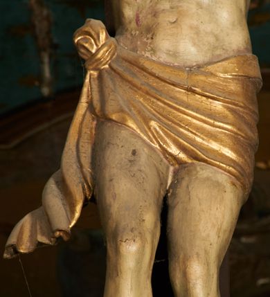 Zdjęcie nr 9: Pełnoplastyczna figura Chrystusa umarłego przybita trzema gwoździami do krzyża o prostym zakończeniu ramion. Ciało w delikatnym zwisie o horyzontalnie rozłożonych ramionach, głowa opadająca na praw bark, nogi lekko ugięte w kolanach, stopy skrzyżowane w układzie prawa na lewą. Chrystus ma pociągłą twarz, o głęboko osadzonych, zamkniętych oczach, długim, wąskim nosie i ustach o opadających kącikach, okoloną falowaną, trójkątną brodą oraz skręconymi w rurkowate pukle włosami. Na głowie ma złoconą koronę cierniową. Ciało szczupłe, wydłużone, o guzowato rzeźbionych mięśniach i żebrach klatki piersiowej oraz wygiętych stopach z podkreślonymi ścięgnami. Perizonium złocone, krótkie, ściśle przylegające do ciała, zawiązane na prawym boku, z lekko rozwianym zwisem tkaniny. Polichromia ciała naturalistyczna. 
U szczytu pionowej belki krzyża tabliczka z malowanym napisem „I.N.R.I.”, pod stopami Chrystusa przybite do krzyża wota.