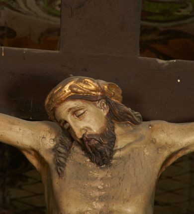 Zdjęcie nr 4: Pełnoplastyczna figura Chrystusa umarłego przybita trzema gwoździami do krzyża o prostym zakończeniu ramion. Ciało w delikatnym zwisie o horyzontalnie rozłożonych ramionach, głowa opadająca na praw bark, nogi lekko ugięte w kolanach, stopy skrzyżowane w układzie prawa na lewą. Chrystus ma pociągłą twarz, o głęboko osadzonych, zamkniętych oczach, długim, wąskim nosie i ustach o opadających kącikach, okoloną falowaną, trójkątną brodą oraz skręconymi w rurkowate pukle włosami. Na głowie ma złoconą koronę cierniową. Ciało szczupłe, wydłużone, o guzowato rzeźbionych mięśniach i żebrach klatki piersiowej oraz wygiętych stopach z podkreślonymi ścięgnami. Perizonium złocone, krótkie, ściśle przylegające do ciała, zawiązane na prawym boku, z lekko rozwianym zwisem tkaniny. Polichromia ciała naturalistyczna. 
U szczytu pionowej belki krzyża tabliczka z malowanym napisem „I.N.R.I.”, pod stopami Chrystusa przybite do krzyża wota.