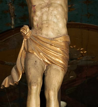 Zdjęcie nr 8: Pełnoplastyczna figura Chrystusa umarłego przybita trzema gwoździami do krzyża o prostym zakończeniu ramion. Ciało w delikatnym zwisie o horyzontalnie rozłożonych ramionach, głowa opadająca na praw bark, nogi lekko ugięte w kolanach, stopy skrzyżowane w układzie prawa na lewą. Chrystus ma pociągłą twarz, o głęboko osadzonych, zamkniętych oczach, długim, wąskim nosie i ustach o opadających kącikach, okoloną falowaną, trójkątną brodą oraz skręconymi w rurkowate pukle włosami. Na głowie ma złoconą koronę cierniową. Ciało szczupłe, wydłużone, o guzowato rzeźbionych mięśniach i żebrach klatki piersiowej oraz wygiętych stopach z podkreślonymi ścięgnami. Perizonium złocone, krótkie, ściśle przylegające do ciała, zawiązane na prawym boku, z lekko rozwianym zwisem tkaniny. Polichromia ciała naturalistyczna. 
U szczytu pionowej belki krzyża tabliczka z malowanym napisem „I.N.R.I.”, pod stopami Chrystusa przybite do krzyża wota.
