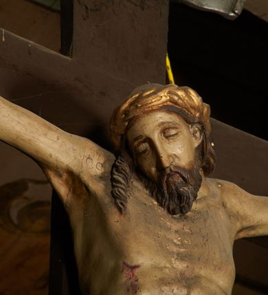 Zdjęcie nr 5: Pełnoplastyczna figura Chrystusa umarłego przybita trzema gwoździami do krzyża o prostym zakończeniu ramion. Ciało w delikatnym zwisie o horyzontalnie rozłożonych ramionach, głowa opadająca na praw bark, nogi lekko ugięte w kolanach, stopy skrzyżowane w układzie prawa na lewą. Chrystus ma pociągłą twarz, o głęboko osadzonych, zamkniętych oczach, długim, wąskim nosie i ustach o opadających kącikach, okoloną falowaną, trójkątną brodą oraz skręconymi w rurkowate pukle włosami. Na głowie ma złoconą koronę cierniową. Ciało szczupłe, wydłużone, o guzowato rzeźbionych mięśniach i żebrach klatki piersiowej oraz wygiętych stopach z podkreślonymi ścięgnami. Perizonium złocone, krótkie, ściśle przylegające do ciała, zawiązane na prawym boku, z lekko rozwianym zwisem tkaniny. Polichromia ciała naturalistyczna. 
U szczytu pionowej belki krzyża tabliczka z malowanym napisem „I.N.R.I.”, pod stopami Chrystusa przybite do krzyża wota.