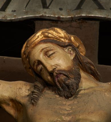 Zdjęcie nr 7: Pełnoplastyczna figura Chrystusa umarłego przybita trzema gwoździami do krzyża o prostym zakończeniu ramion. Ciało w delikatnym zwisie o horyzontalnie rozłożonych ramionach, głowa opadająca na praw bark, nogi lekko ugięte w kolanach, stopy skrzyżowane w układzie prawa na lewą. Chrystus ma pociągłą twarz, o głęboko osadzonych, zamkniętych oczach, długim, wąskim nosie i ustach o opadających kącikach, okoloną falowaną, trójkątną brodą oraz skręconymi w rurkowate pukle włosami. Na głowie ma złoconą koronę cierniową. Ciało szczupłe, wydłużone, o guzowato rzeźbionych mięśniach i żebrach klatki piersiowej oraz wygiętych stopach z podkreślonymi ścięgnami. Perizonium złocone, krótkie, ściśle przylegające do ciała, zawiązane na prawym boku, z lekko rozwianym zwisem tkaniny. Polichromia ciała naturalistyczna. 
U szczytu pionowej belki krzyża tabliczka z malowanym napisem „I.N.R.I.”, pod stopami Chrystusa przybite do krzyża wota.