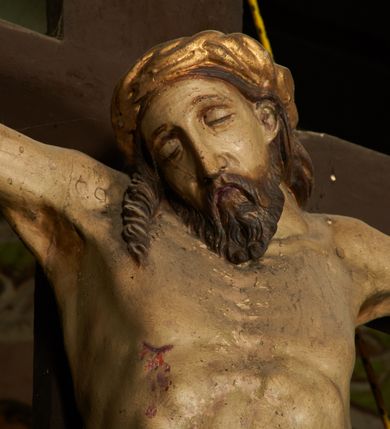 Zdjęcie nr 6: Pełnoplastyczna figura Chrystusa umarłego przybita trzema gwoździami do krzyża o prostym zakończeniu ramion. Ciało w delikatnym zwisie o horyzontalnie rozłożonych ramionach, głowa opadająca na praw bark, nogi lekko ugięte w kolanach, stopy skrzyżowane w układzie prawa na lewą. Chrystus ma pociągłą twarz, o głęboko osadzonych, zamkniętych oczach, długim, wąskim nosie i ustach o opadających kącikach, okoloną falowaną, trójkątną brodą oraz skręconymi w rurkowate pukle włosami. Na głowie ma złoconą koronę cierniową. Ciało szczupłe, wydłużone, o guzowato rzeźbionych mięśniach i żebrach klatki piersiowej oraz wygiętych stopach z podkreślonymi ścięgnami. Perizonium złocone, krótkie, ściśle przylegające do ciała, zawiązane na prawym boku, z lekko rozwianym zwisem tkaniny. Polichromia ciała naturalistyczna. 
U szczytu pionowej belki krzyża tabliczka z malowanym napisem „I.N.R.I.”, pod stopami Chrystusa przybite do krzyża wota.