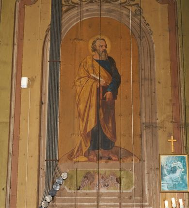 Zdjęcie nr 20: Polichromia ścian kościoła odpowiada podziałom architektonicznym wnętrza wydzielonym przez pilastry, filary i kolumny (w prezbiterium iluzjonistyczne pilastry). Malowany jasnobrązowy cokół w jednej czwartej wysokości ścian zamknięty jest profilowanym gzymsem, w jego polu znajdują się jasnozielone malowane płyciny odpowiadające szerokości podziałów wnętrza. Trzony pilastrów bladoróżowe z malowanymi czerwonymi płycinami, w prezbiterium z kapitelami korynckimi, w nawie zakończone tryglifami. Podpory podtrzymują malowane belkowanie, z jasnoróżowym fryzem i wspornikami dekorowanymi anthemionami, dźwigającymi silnie wysunięty gzyms. W nawie belkowanie malowane jest w partii środkowej (bez zaskrzynień) podtrzymywanej przez filary i kolumny. W polach pomiędzy pilastrami malowane płyciny w formie prostokątów, o szerokości przęseł, ujęte ramą dekorowaną w narożach stylizowanym akantem z kampanulami. W prezbiterium w jasnożółtych płycinach znajdują się malowane nisze w formie stojącego prostokąta zamkniętego łukiem półkolistym, ujęte profilowaną ramą, dekorowaną u góry i u dołu ornamentem roślinnym, z przedstawieniami ewangelistów i ich symboli. Na ścianie północnej znajdują się św. Mateusz, św. Marek i św. Łukasz, a na ścianie południowej, pomiędzy okami św. Jan. W nawie jasnożółte płyciny ścian wypełnione są dekoracją geometryczną w formie niebieskich i żółtych równoramiennych krzyżyków. Otwory okienne, drzwiowe i arkada kaplicy ujęte są malowanymi, imitującymi profilowanie obramieniami, dekorowanymi ornamentem roślinnym. 
Strop prezbiterium i nawy w malowanej, kolorowej, profilowanej ramie, po wewnętrznej stronie z zielono-różowym pasem zdobionym ornamentem. Pośrodku, na tle malowanej jasnoróżowej płyciny, wydzielone pole o fantazyjnym kształcie, obwiedzione pomarańczową opaską z kartuszami na każdej stronie, ujętymi ornamentem roślinnym, wypełnionymi kratką i fantazyjną dekoracją. Jasnoniebieskie pole wypełnione jest malowanymi na złoto gwiazdami. W prezbiterium, w jego centrum kolejne pole o analogicznym kształcie ze sceną Wniebowzięcia Marii, a w nawie dwa pola ze scenami Chrystusa Zmartwychwstałego i Świętej Rodziny. W partii zaskrzynień nawy malowane płyciny w zielonych opaskach i jasnoróżowych polach wypełnione ornamentem geometrycznym. Jasnozielona balustrada chóru muzycznego dekorowana malowanymi płycinami w formie prostokątów, naprzemiennie stojących i leżących, flankujących środkowy medalion, wszystkie ujęte profilowaną ramą. Pola prostokątów stojących wypełnione rozetami na jasnoczerwonym tle. Pola prostokątów leżących wypełnione przedstawieniami instrumentów i ornamentu roślinnego ukazanych na żółtym tle. W środkowym medalionie przedstawienie Dawida grającego na harfie. 















