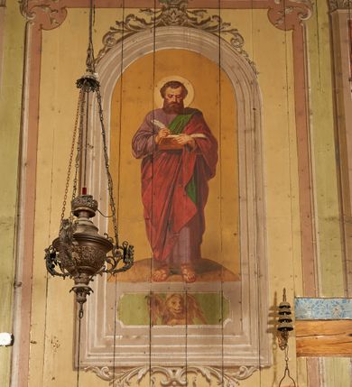 Zdjęcie nr 13: Polichromia ścian kościoła odpowiada podziałom architektonicznym wnętrza wydzielonym przez pilastry, filary i kolumny (w prezbiterium iluzjonistyczne pilastry). Malowany jasnobrązowy cokół w jednej czwartej wysokości ścian zamknięty jest profilowanym gzymsem, w jego polu znajdują się jasnozielone malowane płyciny odpowiadające szerokości podziałów wnętrza. Trzony pilastrów bladoróżowe z malowanymi czerwonymi płycinami, w prezbiterium z kapitelami korynckimi, w nawie zakończone tryglifami. Podpory podtrzymują malowane belkowanie, z jasnoróżowym fryzem i wspornikami dekorowanymi anthemionami, dźwigającymi silnie wysunięty gzyms. W nawie belkowanie malowane jest w partii środkowej (bez zaskrzynień) podtrzymywanej przez filary i kolumny. W polach pomiędzy pilastrami malowane płyciny w formie prostokątów, o szerokości przęseł, ujęte ramą dekorowaną w narożach stylizowanym akantem z kampanulami. W prezbiterium w jasnożółtych płycinach znajdują się malowane nisze w formie stojącego prostokąta zamkniętego łukiem półkolistym, ujęte profilowaną ramą, dekorowaną u góry i u dołu ornamentem roślinnym, z przedstawieniami ewangelistów i ich symboli. Na ścianie północnej znajdują się św. Mateusz, św. Marek i św. Łukasz, a na ścianie południowej, pomiędzy okami św. Jan. W nawie jasnożółte płyciny ścian wypełnione są dekoracją geometryczną w formie niebieskich i żółtych równoramiennych krzyżyków. Otwory okienne, drzwiowe i arkada kaplicy ujęte są malowanymi, imitującymi profilowanie obramieniami, dekorowanymi ornamentem roślinnym. 
Strop prezbiterium i nawy w malowanej, kolorowej, profilowanej ramie, po wewnętrznej stronie z zielono-różowym pasem zdobionym ornamentem. Pośrodku, na tle malowanej jasnoróżowej płyciny, wydzielone pole o fantazyjnym kształcie, obwiedzione pomarańczową opaską z kartuszami na każdej stronie, ujętymi ornamentem roślinnym, wypełnionymi kratką i fantazyjną dekoracją. Jasnoniebieskie pole wypełnione jest malowanymi na złoto gwiazdami. W prezbiterium, w jego centrum kolejne pole o analogicznym kształcie ze sceną Wniebowzięcia Marii, a w nawie dwa pola ze scenami Chrystusa Zmartwychwstałego i Świętej Rodziny. W partii zaskrzynień nawy malowane płyciny w zielonych opaskach i jasnoróżowych polach wypełnione ornamentem geometrycznym. Jasnozielona balustrada chóru muzycznego dekorowana malowanymi płycinami w formie prostokątów, naprzemiennie stojących i leżących, flankujących środkowy medalion, wszystkie ujęte profilowaną ramą. Pola prostokątów stojących wypełnione rozetami na jasnoczerwonym tle. Pola prostokątów leżących wypełnione przedstawieniami instrumentów i ornamentu roślinnego ukazanych na żółtym tle. W środkowym medalionie przedstawienie Dawida grającego na harfie. 















