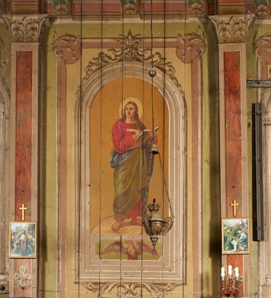 Zdjęcie nr 22: Polichromia ścian kościoła odpowiada podziałom architektonicznym wnętrza wydzielonym przez pilastry, filary i kolumny (w prezbiterium iluzjonistyczne pilastry). Malowany jasnobrązowy cokół w jednej czwartej wysokości ścian zamknięty jest profilowanym gzymsem, w jego polu znajdują się jasnozielone malowane płyciny odpowiadające szerokości podziałów wnętrza. Trzony pilastrów bladoróżowe z malowanymi czerwonymi płycinami, w prezbiterium z kapitelami korynckimi, w nawie zakończone tryglifami. Podpory podtrzymują malowane belkowanie, z jasnoróżowym fryzem i wspornikami dekorowanymi anthemionami, dźwigającymi silnie wysunięty gzyms. W nawie belkowanie malowane jest w partii środkowej (bez zaskrzynień) podtrzymywanej przez filary i kolumny. W polach pomiędzy pilastrami malowane płyciny w formie prostokątów, o szerokości przęseł, ujęte ramą dekorowaną w narożach stylizowanym akantem z kampanulami. W prezbiterium w jasnożółtych płycinach znajdują się malowane nisze w formie stojącego prostokąta zamkniętego łukiem półkolistym, ujęte profilowaną ramą, dekorowaną u góry i u dołu ornamentem roślinnym, z przedstawieniami ewangelistów i ich symboli. Na ścianie północnej znajdują się św. Mateusz, św. Marek i św. Łukasz, a na ścianie południowej, pomiędzy okami św. Jan. W nawie jasnożółte płyciny ścian wypełnione są dekoracją geometryczną w formie niebieskich i żółtych równoramiennych krzyżyków. Otwory okienne, drzwiowe i arkada kaplicy ujęte są malowanymi, imitującymi profilowanie obramieniami, dekorowanymi ornamentem roślinnym. 
Strop prezbiterium i nawy w malowanej, kolorowej, profilowanej ramie, po wewnętrznej stronie z zielono-różowym pasem zdobionym ornamentem. Pośrodku, na tle malowanej jasnoróżowej płyciny, wydzielone pole o fantazyjnym kształcie, obwiedzione pomarańczową opaską z kartuszami na każdej stronie, ujętymi ornamentem roślinnym, wypełnionymi kratką i fantazyjną dekoracją. Jasnoniebieskie pole wypełnione jest malowanymi na złoto gwiazdami. W prezbiterium, w jego centrum kolejne pole o analogicznym kształcie ze sceną Wniebowzięcia Marii, a w nawie dwa pola ze scenami Chrystusa Zmartwychwstałego i Świętej Rodziny. W partii zaskrzynień nawy malowane płyciny w zielonych opaskach i jasnoróżowych polach wypełnione ornamentem geometrycznym. Jasnozielona balustrada chóru muzycznego dekorowana malowanymi płycinami w formie prostokątów, naprzemiennie stojących i leżących, flankujących środkowy medalion, wszystkie ujęte profilowaną ramą. Pola prostokątów stojących wypełnione rozetami na jasnoczerwonym tle. Pola prostokątów leżących wypełnione przedstawieniami instrumentów i ornamentu roślinnego ukazanych na żółtym tle. W środkowym medalionie przedstawienie Dawida grającego na harfie. 















