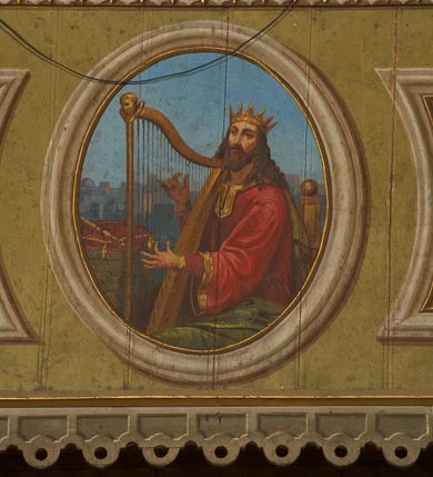 Zdjęcie nr 10: Polichromia ścian kościoła odpowiada podziałom architektonicznym wnętrza wydzielonym przez pilastry, filary i kolumny (w prezbiterium iluzjonistyczne pilastry). Malowany jasnobrązowy cokół w jednej czwartej wysokości ścian zamknięty jest profilowanym gzymsem, w jego polu znajdują się jasnozielone malowane płyciny odpowiadające szerokości podziałów wnętrza. Trzony pilastrów bladoróżowe z malowanymi czerwonymi płycinami, w prezbiterium z kapitelami korynckimi, w nawie zakończone tryglifami. Podpory podtrzymują malowane belkowanie, z jasnoróżowym fryzem i wspornikami dekorowanymi anthemionami, dźwigającymi silnie wysunięty gzyms. W nawie belkowanie malowane jest w partii środkowej (bez zaskrzynień) podtrzymywanej przez filary i kolumny. W polach pomiędzy pilastrami malowane płyciny w formie prostokątów, o szerokości przęseł, ujęte ramą dekorowaną w narożach stylizowanym akantem z kampanulami. W prezbiterium w jasnożółtych płycinach znajdują się malowane nisze w formie stojącego prostokąta zamkniętego łukiem półkolistym, ujęte profilowaną ramą, dekorowaną u góry i u dołu ornamentem roślinnym, z przedstawieniami ewangelistów i ich symboli. Na ścianie północnej znajdują się św. Mateusz, św. Marek i św. Łukasz, a na ścianie południowej, pomiędzy okami św. Jan. W nawie jasnożółte płyciny ścian wypełnione są dekoracją geometryczną w formie niebieskich i żółtych równoramiennych krzyżyków. Otwory okienne, drzwiowe i arkada kaplicy ujęte są malowanymi, imitującymi profilowanie obramieniami, dekorowanymi ornamentem roślinnym. 
Strop prezbiterium i nawy w malowanej, kolorowej, profilowanej ramie, po wewnętrznej stronie z zielono-różowym pasem zdobionym ornamentem. Pośrodku, na tle malowanej jasnoróżowej płyciny, wydzielone pole o fantazyjnym kształcie, obwiedzione pomarańczową opaską z kartuszami na każdej stronie, ujętymi ornamentem roślinnym, wypełnionymi kratką i fantazyjną dekoracją. Jasnoniebieskie pole wypełnione jest malowanymi na złoto gwiazdami. W prezbiterium, w jego centrum kolejne pole o analogicznym kształcie ze sceną Wniebowzięcia Marii, a w nawie dwa pola ze scenami Chrystusa Zmartwychwstałego i Świętej Rodziny. W partii zaskrzynień nawy malowane płyciny w zielonych opaskach i jasnoróżowych polach wypełnione ornamentem geometrycznym. Jasnozielona balustrada chóru muzycznego dekorowana malowanymi płycinami w formie prostokątów, naprzemiennie stojących i leżących, flankujących środkowy medalion, wszystkie ujęte profilowaną ramą. Pola prostokątów stojących wypełnione rozetami na jasnoczerwonym tle. Pola prostokątów leżących wypełnione przedstawieniami instrumentów i ornamentu roślinnego ukazanych na żółtym tle. W środkowym medalionie przedstawienie Dawida grającego na harfie. 















