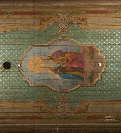 Zdjęcie nr 26: Polichromia ścian kościoła odpowiada podziałom architektonicznym wnętrza wydzielonym przez pilastry, filary i kolumny (w prezbiterium iluzjonistyczne pilastry). Malowany jasnobrązowy cokół w jednej czwartej wysokości ścian zamknięty jest profilowanym gzymsem, w jego polu znajdują się jasnozielone malowane płyciny odpowiadające szerokości podziałów wnętrza. Trzony pilastrów bladoróżowe z malowanymi czerwonymi płycinami, w prezbiterium z kapitelami korynckimi, w nawie zakończone tryglifami. Podpory podtrzymują malowane belkowanie, z jasnoróżowym fryzem i wspornikami dekorowanymi anthemionami, dźwigającymi silnie wysunięty gzyms. W nawie belkowanie malowane jest w partii środkowej (bez zaskrzynień) podtrzymywanej przez filary i kolumny. W polach pomiędzy pilastrami malowane płyciny w formie prostokątów, o szerokości przęseł, ujęte ramą dekorowaną w narożach stylizowanym akantem z kampanulami. W prezbiterium w jasnożółtych płycinach znajdują się malowane nisze w formie stojącego prostokąta zamkniętego łukiem półkolistym, ujęte profilowaną ramą, dekorowaną u góry i u dołu ornamentem roślinnym, z przedstawieniami ewangelistów i ich symboli. Na ścianie północnej znajdują się św. Mateusz, św. Marek i św. Łukasz, a na ścianie południowej, pomiędzy okami św. Jan. W nawie jasnożółte płyciny ścian wypełnione są dekoracją geometryczną w formie niebieskich i żółtych równoramiennych krzyżyków. Otwory okienne, drzwiowe i arkada kaplicy ujęte są malowanymi, imitującymi profilowanie obramieniami, dekorowanymi ornamentem roślinnym. 
Strop prezbiterium i nawy w malowanej, kolorowej, profilowanej ramie, po wewnętrznej stronie z zielono-różowym pasem zdobionym ornamentem. Pośrodku, na tle malowanej jasnoróżowej płyciny, wydzielone pole o fantazyjnym kształcie, obwiedzione pomarańczową opaską z kartuszami na każdej stronie, ujętymi ornamentem roślinnym, wypełnionymi kratką i fantazyjną dekoracją. Jasnoniebieskie pole wypełnione jest malowanymi na złoto gwiazdami. W prezbiterium, w jego centrum kolejne pole o analogicznym kształcie ze sceną Wniebowzięcia Marii, a w nawie dwa pola ze scenami Chrystusa Zmartwychwstałego i Świętej Rodziny. W partii zaskrzynień nawy malowane płyciny w zielonych opaskach i jasnoróżowych polach wypełnione ornamentem geometrycznym. Jasnozielona balustrada chóru muzycznego dekorowana malowanymi płycinami w formie prostokątów, naprzemiennie stojących i leżących, flankujących środkowy medalion, wszystkie ujęte profilowaną ramą. Pola prostokątów stojących wypełnione rozetami na jasnoczerwonym tle. Pola prostokątów leżących wypełnione przedstawieniami instrumentów i ornamentu roślinnego ukazanych na żółtym tle. W środkowym medalionie przedstawienie Dawida grającego na harfie. 















