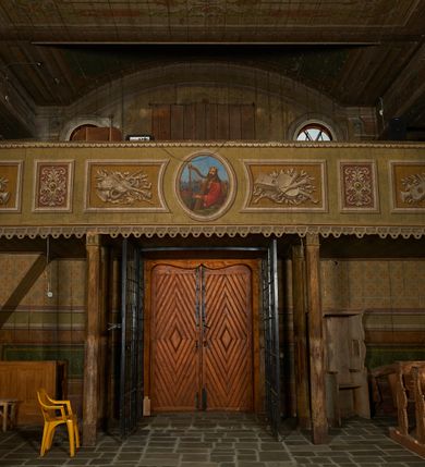 Zdjęcie nr 8: Polichromia ścian kościoła odpowiada podziałom architektonicznym wnętrza wydzielonym przez pilastry, filary i kolumny (w prezbiterium iluzjonistyczne pilastry). Malowany jasnobrązowy cokół w jednej czwartej wysokości ścian zamknięty jest profilowanym gzymsem, w jego polu znajdują się jasnozielone malowane płyciny odpowiadające szerokości podziałów wnętrza. Trzony pilastrów bladoróżowe z malowanymi czerwonymi płycinami, w prezbiterium z kapitelami korynckimi, w nawie zakończone tryglifami. Podpory podtrzymują malowane belkowanie, z jasnoróżowym fryzem i wspornikami dekorowanymi anthemionami, dźwigającymi silnie wysunięty gzyms. W nawie belkowanie malowane jest w partii środkowej (bez zaskrzynień) podtrzymywanej przez filary i kolumny. W polach pomiędzy pilastrami malowane płyciny w formie prostokątów, o szerokości przęseł, ujęte ramą dekorowaną w narożach stylizowanym akantem z kampanulami. W prezbiterium w jasnożółtych płycinach znajdują się malowane nisze w formie stojącego prostokąta zamkniętego łukiem półkolistym, ujęte profilowaną ramą, dekorowaną u góry i u dołu ornamentem roślinnym, z przedstawieniami ewangelistów i ich symboli. Na ścianie północnej znajdują się św. Mateusz, św. Marek i św. Łukasz, a na ścianie południowej, pomiędzy okami św. Jan. W nawie jasnożółte płyciny ścian wypełnione są dekoracją geometryczną w formie niebieskich i żółtych równoramiennych krzyżyków. Otwory okienne, drzwiowe i arkada kaplicy ujęte są malowanymi, imitującymi profilowanie obramieniami, dekorowanymi ornamentem roślinnym. 
Strop prezbiterium i nawy w malowanej, kolorowej, profilowanej ramie, po wewnętrznej stronie z zielono-różowym pasem zdobionym ornamentem. Pośrodku, na tle malowanej jasnoróżowej płyciny, wydzielone pole o fantazyjnym kształcie, obwiedzione pomarańczową opaską z kartuszami na każdej stronie, ujętymi ornamentem roślinnym, wypełnionymi kratką i fantazyjną dekoracją. Jasnoniebieskie pole wypełnione jest malowanymi na złoto gwiazdami. W prezbiterium, w jego centrum kolejne pole o analogicznym kształcie ze sceną Wniebowzięcia Marii, a w nawie dwa pola ze scenami Chrystusa Zmartwychwstałego i Świętej Rodziny. W partii zaskrzynień nawy malowane płyciny w zielonych opaskach i jasnoróżowych polach wypełnione ornamentem geometrycznym. Jasnozielona balustrada chóru muzycznego dekorowana malowanymi płycinami w formie prostokątów, naprzemiennie stojących i leżących, flankujących środkowy medalion, wszystkie ujęte profilowaną ramą. Pola prostokątów stojących wypełnione rozetami na jasnoczerwonym tle. Pola prostokątów leżących wypełnione przedstawieniami instrumentów i ornamentu roślinnego ukazanych na żółtym tle. W środkowym medalionie przedstawienie Dawida grającego na harfie. 















