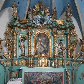 Zdjęcie nr 1: Nastawa ołtarzowa architektoniczna, jednokondygnacyjna, trójosiowa ze zwieńczeniem i z bramkami. Ołtarz prostopadłościenny, drewniany, mensa drewniana z kamiennym portatylem. Antependium w formie leżącego prostokąta ujętego złoconą, profilowaną ramą. W polu obraz malowany olejem na płótnie. W centrum kartusz w kształcie wydłużonego czwórliścia, dekorowany muszlą i wolutami z przedstawieniem pejzażu i widokiem na Golgotę. Po bokach kartusza bujne gałązki kwiatów. Tabernakulum w formie prostopadłościennej skrzynki o wypukłej ścianie frontowej, na profilowanym cokole, zamknięte profilowanym gzymsem, ujęte uszami utworzonymi z liści. Nad drzwiczkami, na gzymsie kartusz z niewielkim krucyfiksem. Powyżej tron wystawienia w formie profilowanej podstawy dekorowanej liśćmi. Na ściance frontowej tabernakulum profilowana rama w kształcie stojącego prostokąta zamkniętego łukiem nadwieszonym, w polu drzwiczki w formie stojącego prostokąta z przedstawieniem kielicha w glorii, powyżej drzwiczek winne grono. 

Nastawa ustawiona na zdwojonym cokole, dekorowanym wijącym się akantem. Osie kondygnacji wydzielone dwiema parami pilastrów oraz ustawionymi ukośnie kolumnami. Podpory dźwigają pełne belkowanie, przerwane nad polem środkowym i wyłamane nad osiami bocznymi, na których skraju ustawiony jest ukośnie przerwany, wolutowy przyczółek. Kolumny o kręconych trzonach, owinięte wicią liści akantu, kapitele korynckie; imposty ustawione pod kątem. W polu środkowym rama w kształcie stojącego prostokąta zamkniętego łukiem półkolistym z obrazem św. Kwiryna. W osiach bocznych płytkie płyciny, zwieńczone konchą z figurami św. Sebastiana po lewej stronie i św. Jana Nepomucena po prawej stronie, ustawionymi na wspornikach. Kondygnacja ujęta jest po bokach szerokimi uszami utworzonymi z liści akantu i karbowanej wstęgi. Fryz nad osiami bocznymi zdobiony kartuszami, we fryzie impostów z dwóch stron rozety; przyłucza osi bocznych dekorowane akantem.

W zwieńczeniu rzeźbiona półpostać Boga Ojca na obłoku z widocznym poniżej fragmentem globu ziemskiego i gołębicą Ducha Świętego; całość ukazana na tle promienistej glorii. Na belkowaniu, na osiach podpór wewnętrznych ustawione są rzeźby: św. Rocha  po lewej stronie i św. Wawrzyńca po prawej, a na zewnętrznych osiach retabulum rzeźby: Karola Boromeusza po lewej stronie i św. Stefana po prawej.

Nastawa ołtarzowa ujęta jest po bokach szerokimi bramkami w kształcie stojących prostokątów z drzwiczkami zamkniętymi półkoliście. Bramki ujęte są pilastrami o kanelowanych trzonach i fantazyjnych kapitelach, wspierających niepełne belkowanie oraz przerwany przyczółek. Nad bramkami ustawione są na cokołach rzeźby: św. Piotra po lewej stronie i św. Pawła po prawej. W polu drzwiczek owalne kartusze z herbem Görgey. W prawym kartuszu opisanym słowami: „BALTHAZAR GÖRGEI SENIOR”. Nad arkadami bramek są muszle, w przyłuczach akant, we fryzie rozety, a przerwany przyczółek dekorowany jest akantem. Struktura w całości polichromowana w odcieniu bladozielonym; ornamentyka, kolumny i profilowania złocone, detale srebrzone.